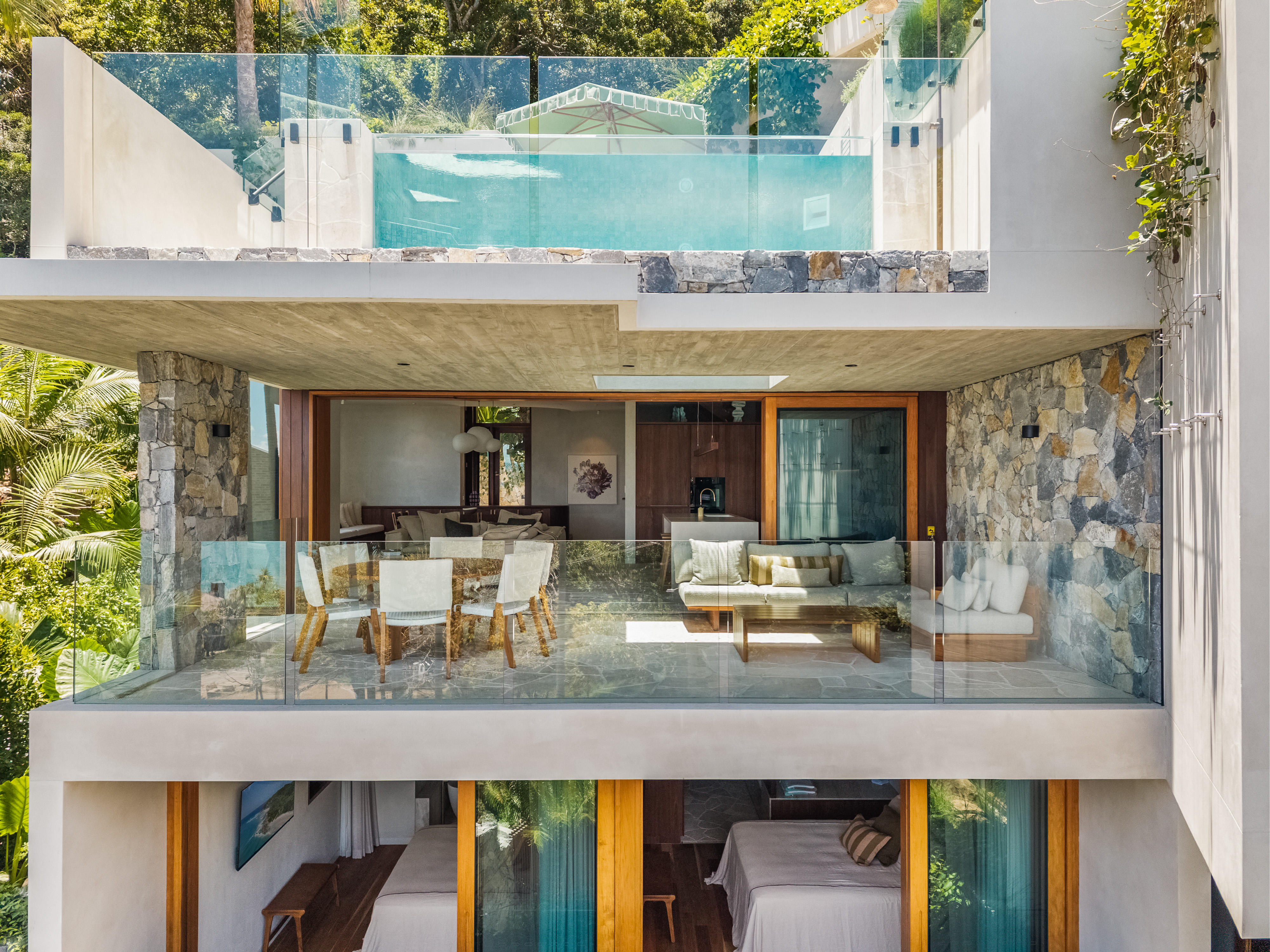 Front facade showing multi-level design with stone, glass and greenery — real estate photography Byron Bay