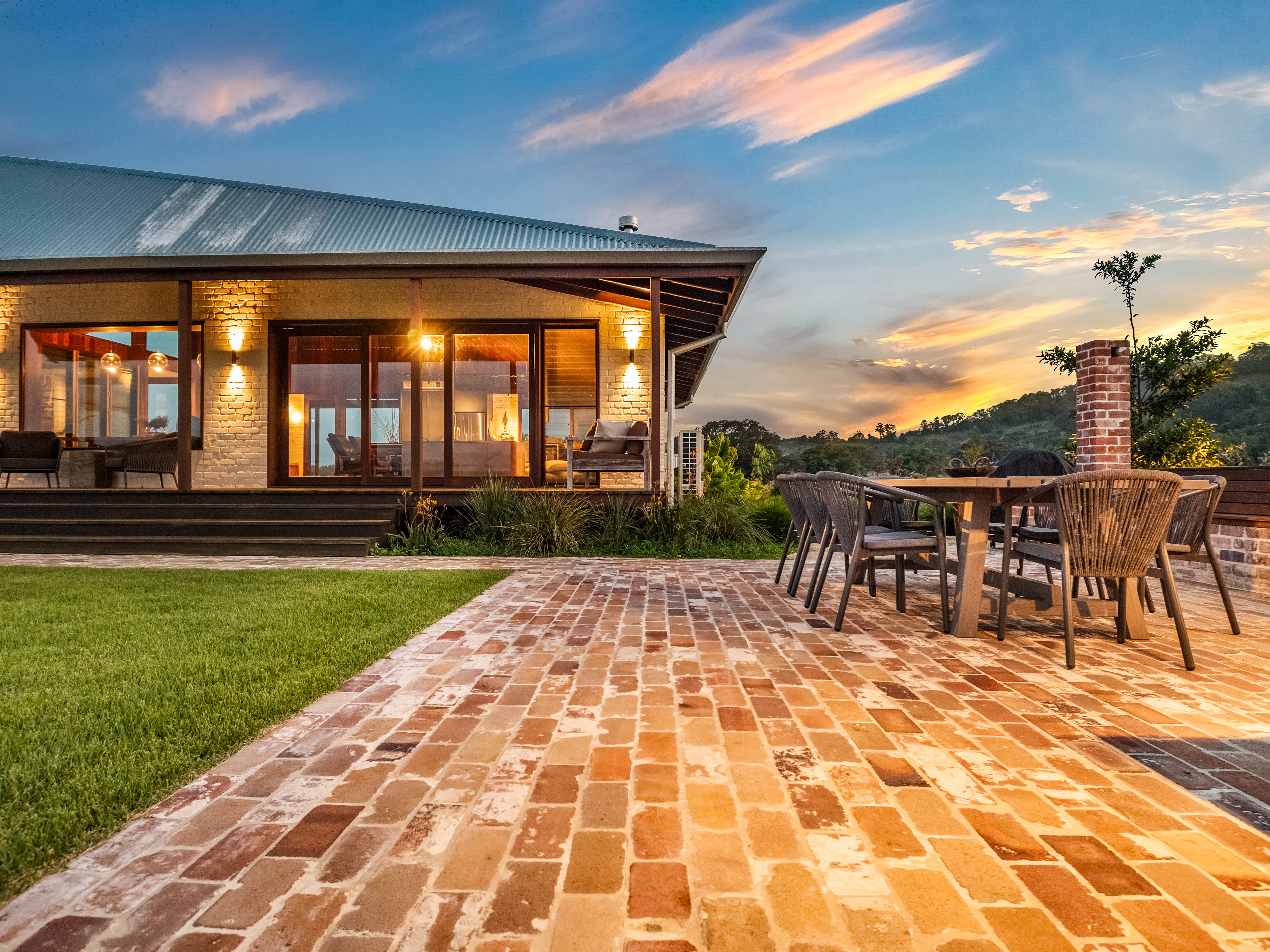 Modern extension at twilight with recycled brick patio and sunset