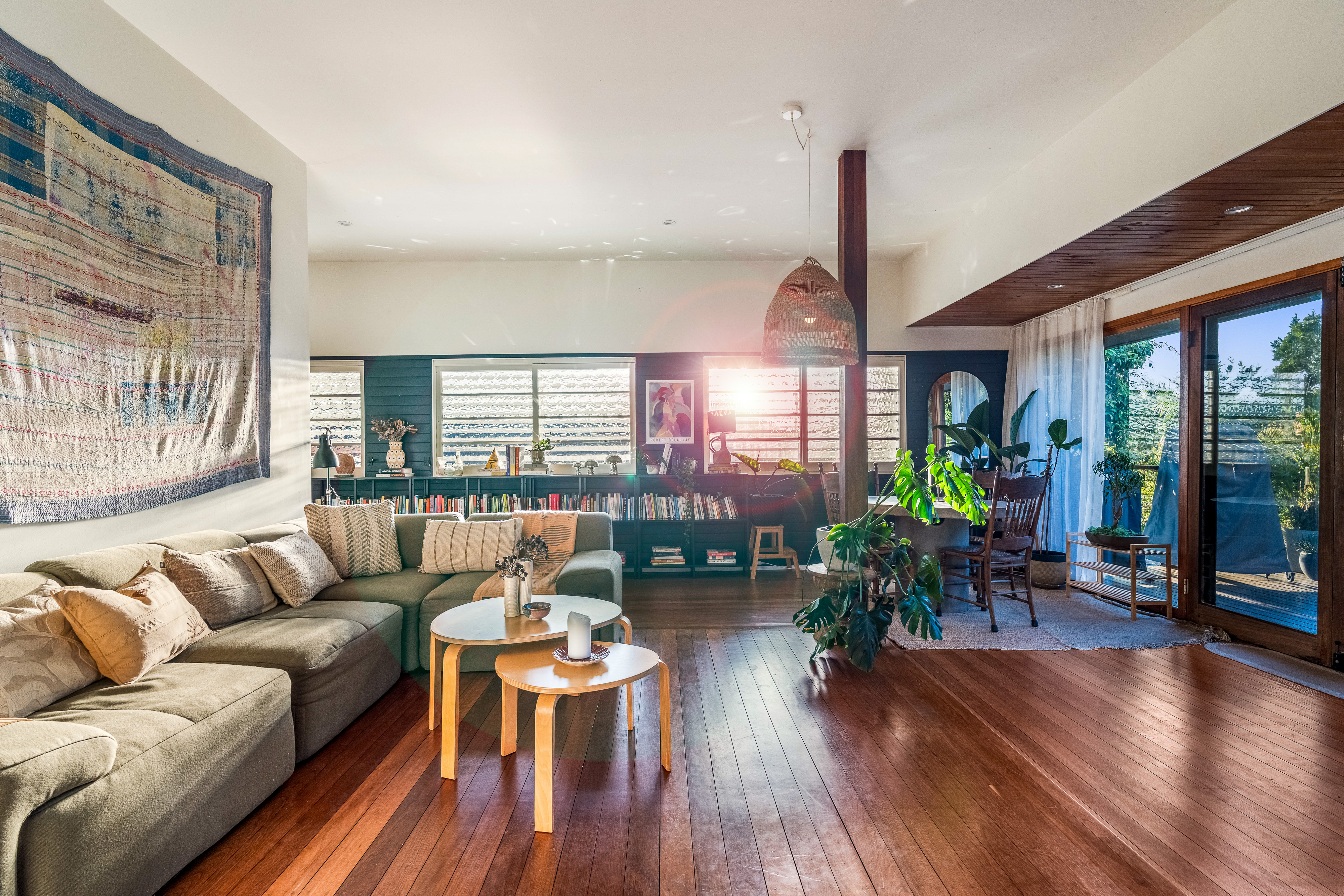 Golden hour living room with hardwood floors and sunset light streaming through louvres at 20 Music Street, East Lismore