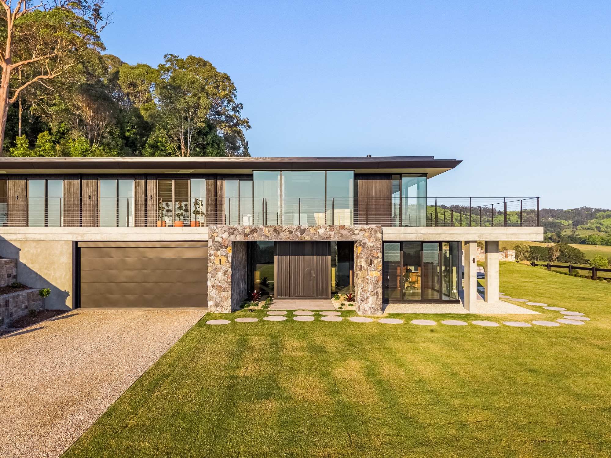 Low-angle drone of front facade with stone and timber cladding