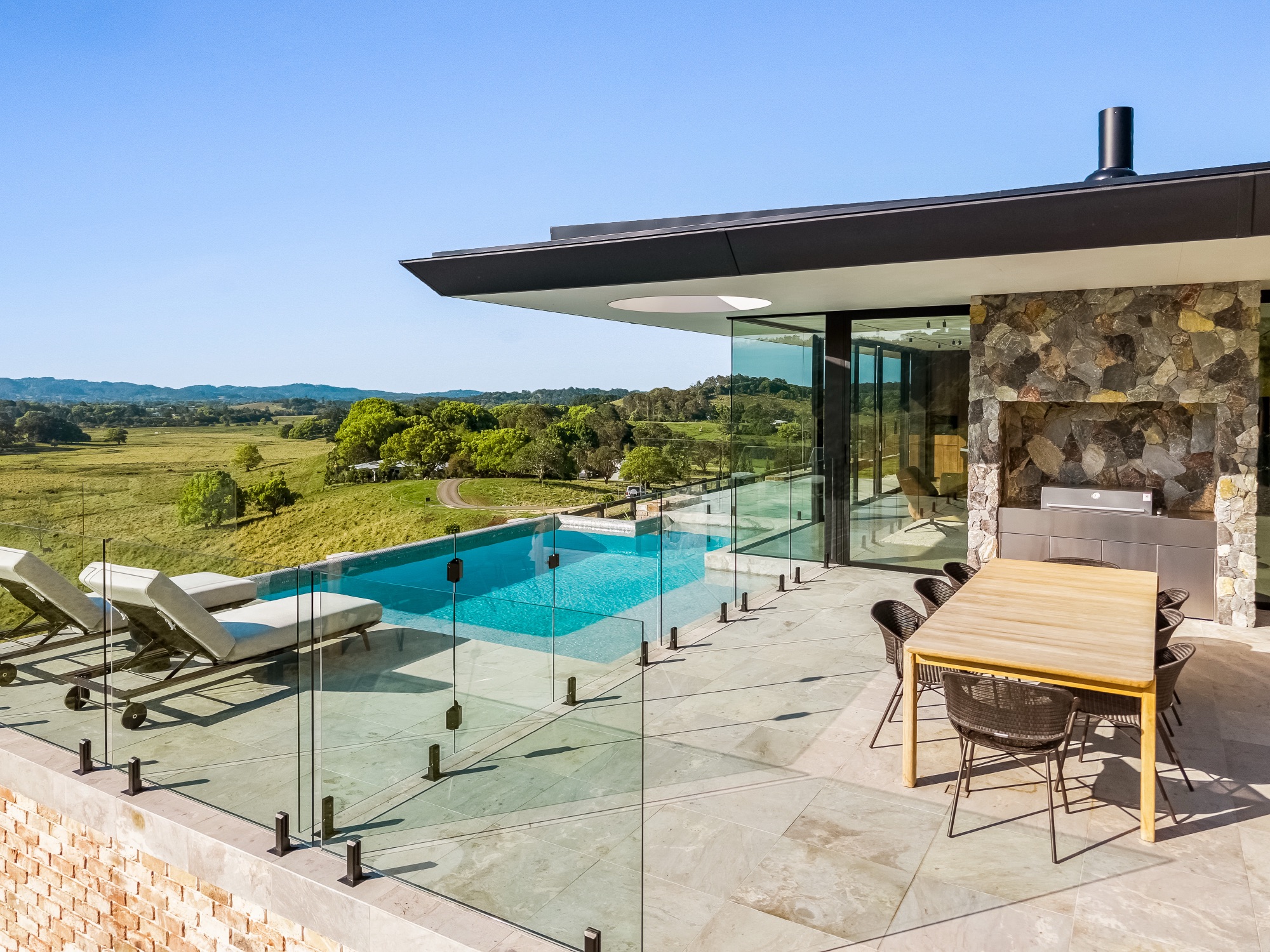 Pool terrace with infinity pool, outdoor dining and stone BBQ area