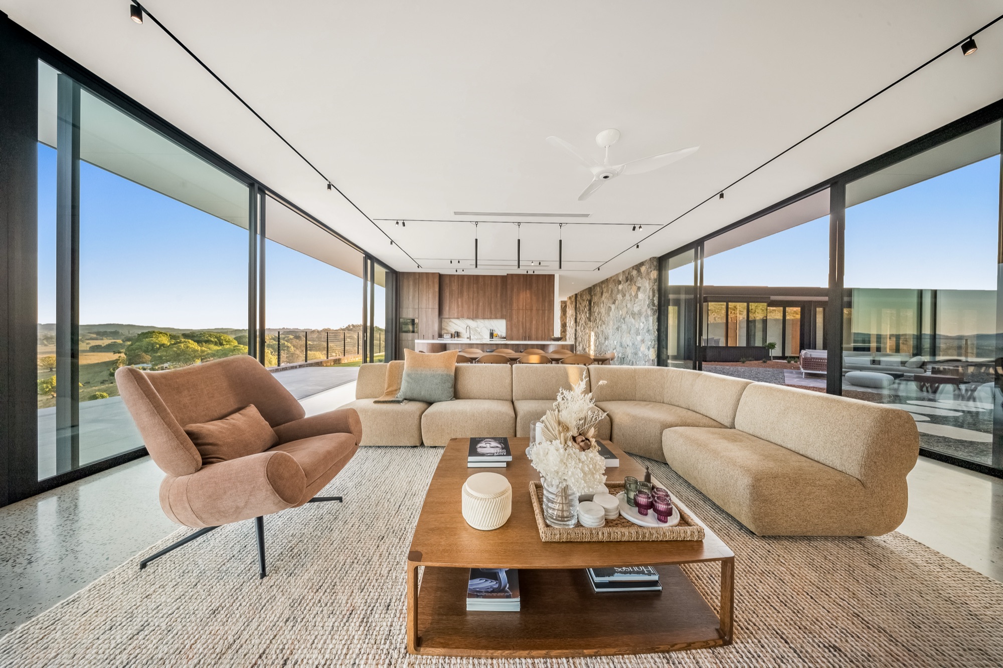 Living area from opposite angle showing full glass walls and hinterland panorama