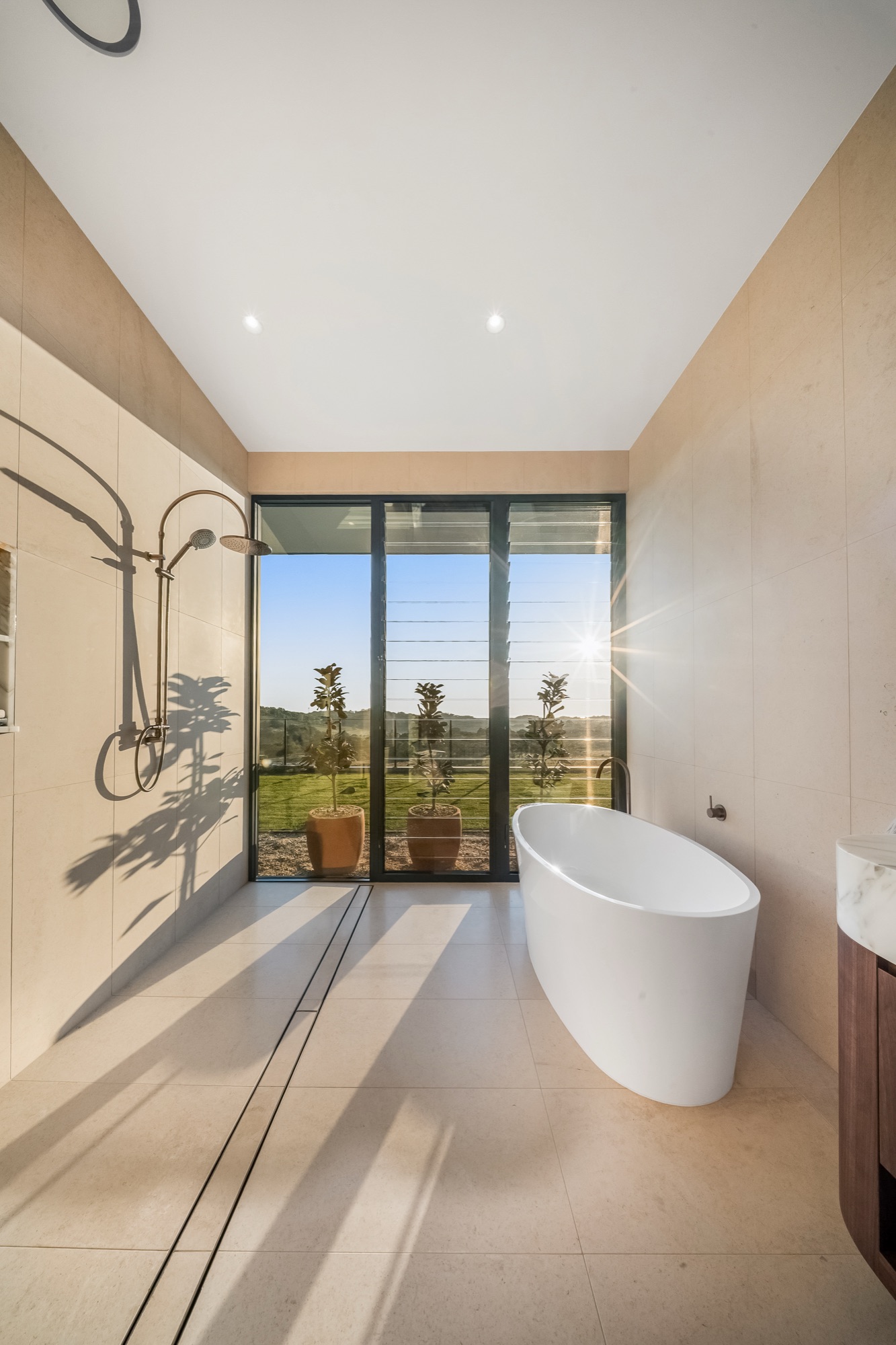 Bathroom with freestanding bath, louvre windows and hinterland views