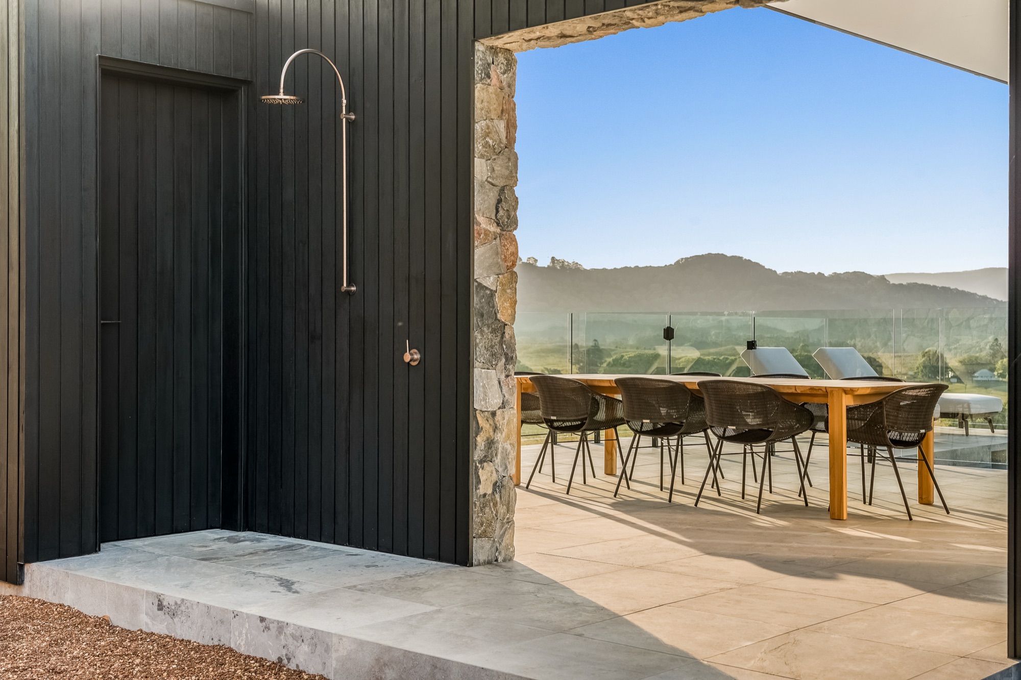 Outdoor shower with stone wall and alfresco dining beyond