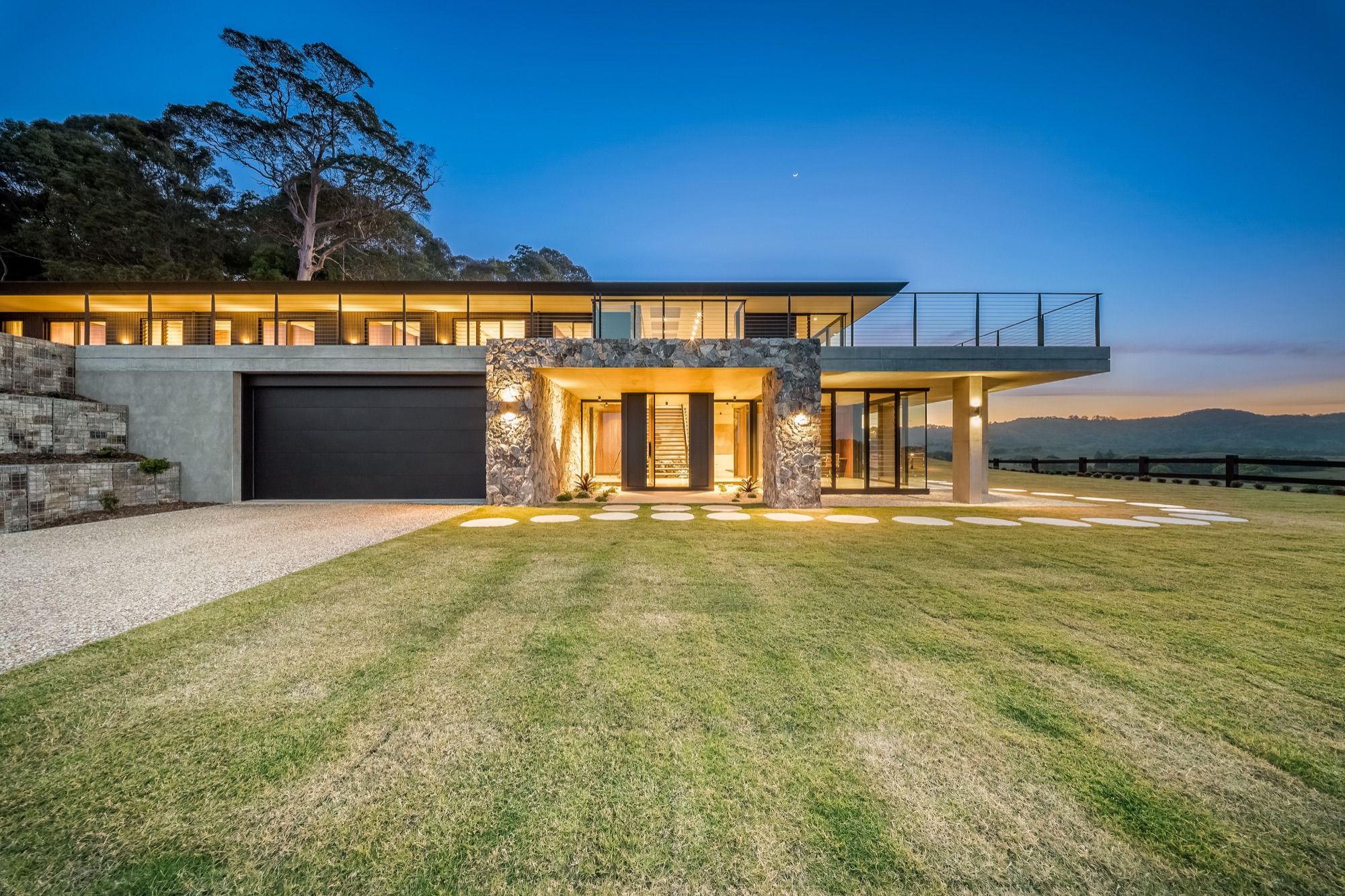 Front facade at twilight with stone, glass and warm lighting