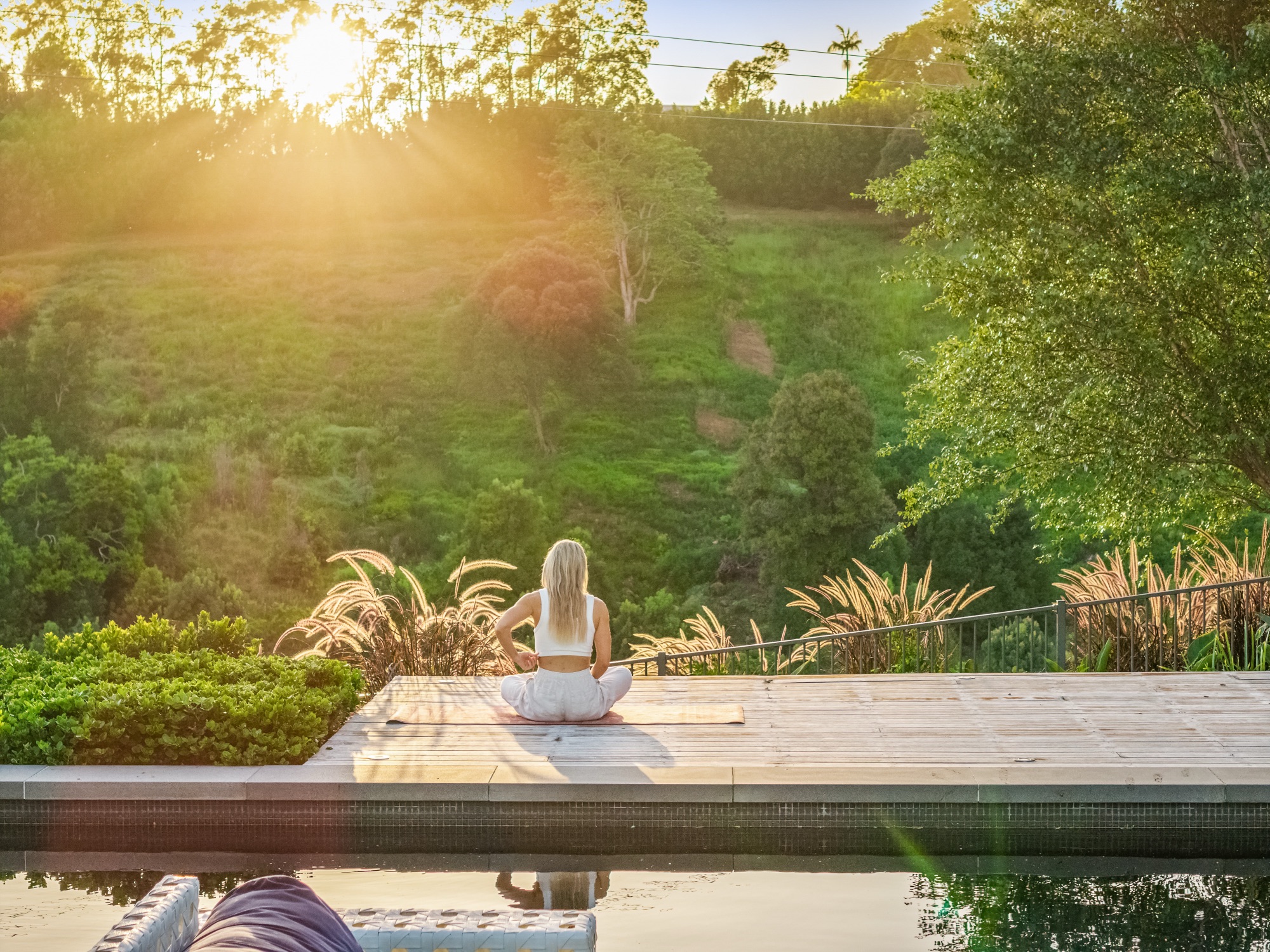 Sunrise yoga on the pool deck with morning light filtering through trees