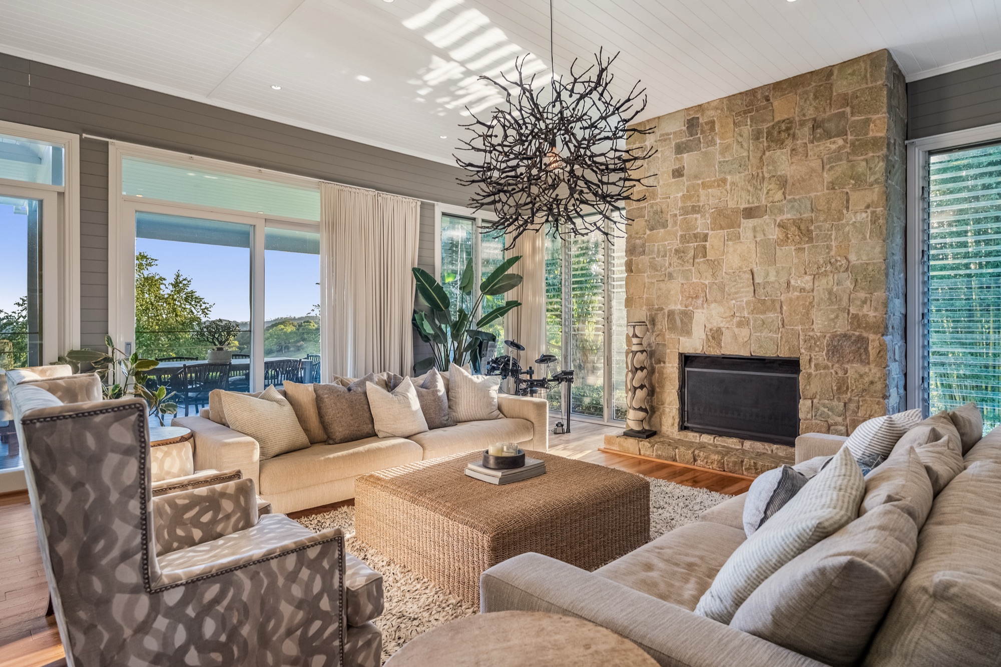 Living room with sandstone fireplace, sculptural branch chandelier and raked VJ ceiling